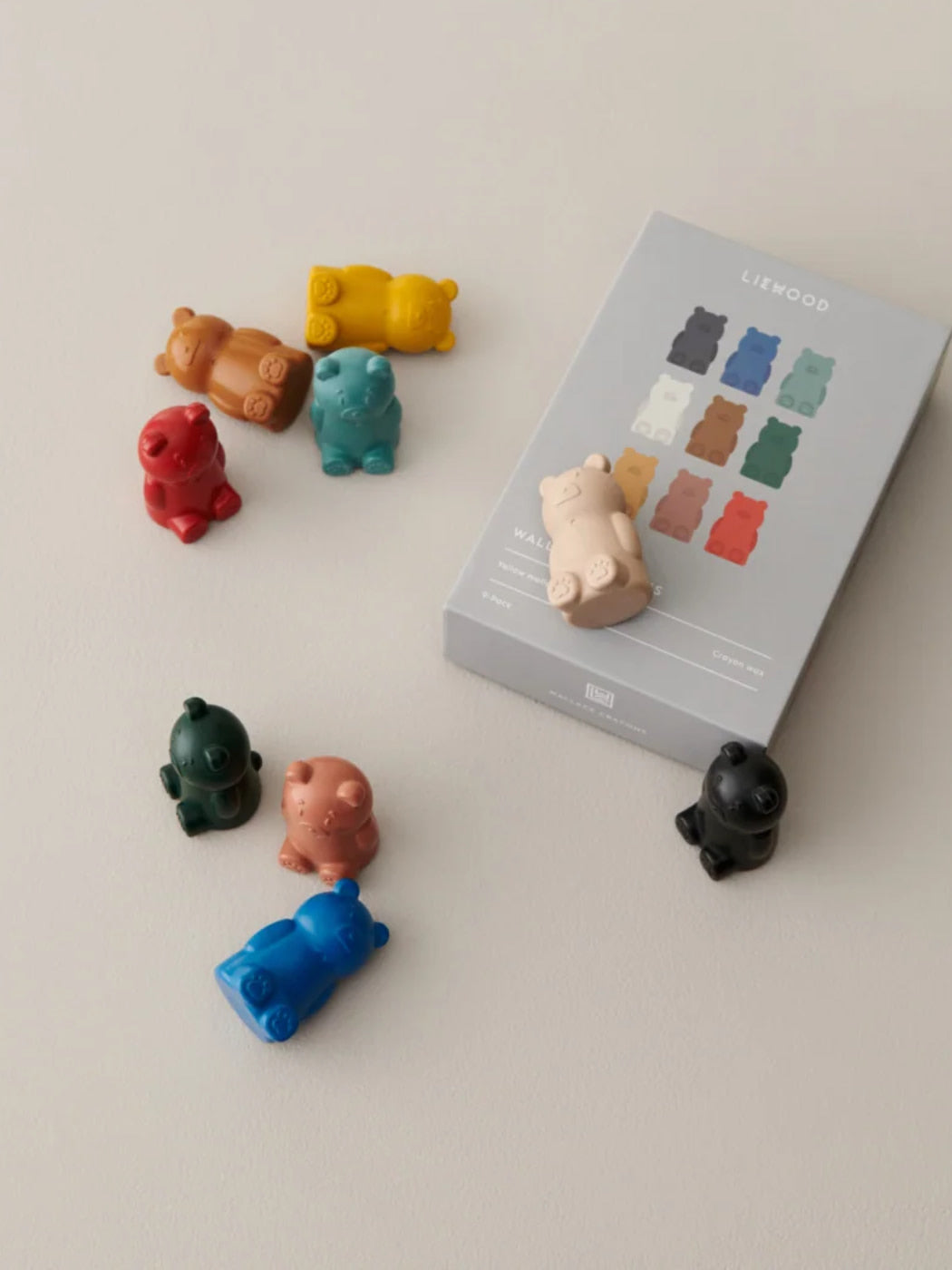 A set of small bear-shaped cayons in multiple colors arranged around a gray product box labeled LIEWOOD on a light beige background.