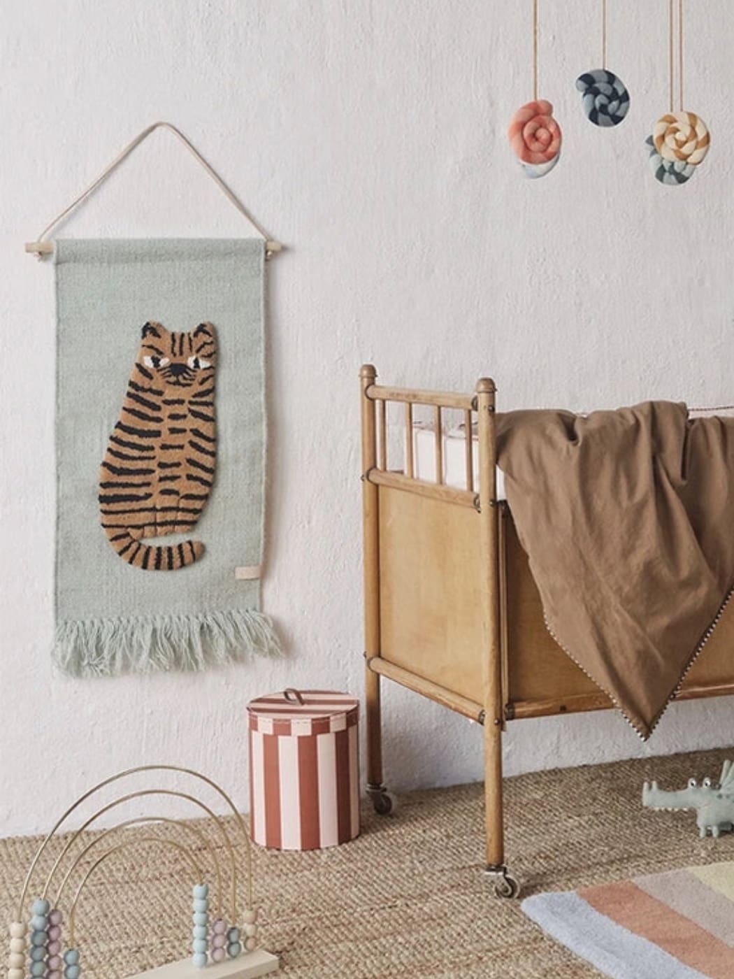 Nursery room with a tiger wall hanging, crib, and colorful mobile.