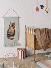 Nursery room with a tiger wall hanging, crib, and colorful mobile.